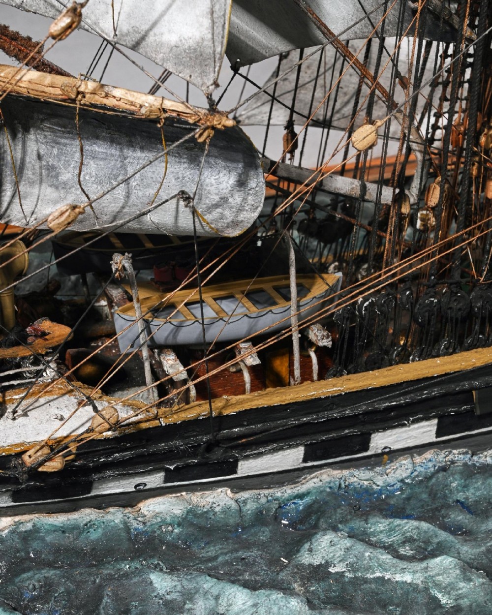 A detailed scale model of a three-masted tea clipper ship in full sail set within a seascaped display inside a glazed oak wood case with a brass plaque. View XII