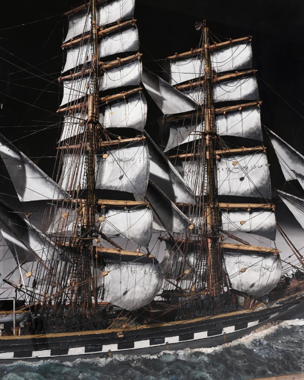 A detailed scale model of a three-masted tea clipper ship in full sail set within a seascaped display inside a glazed oak wood case with a brass plaque. View XIII