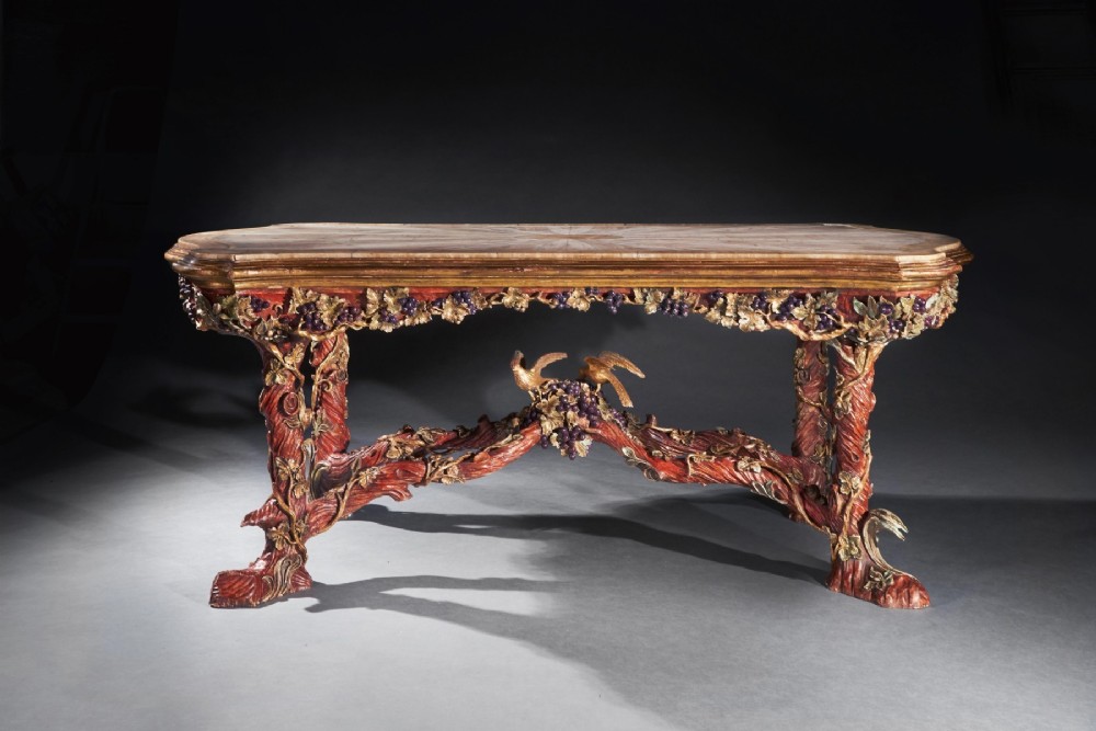 An ornate Italian centre table featuring a sunburst pattern onyx top supported by a sculpted polychrome and gilded wooden frame shaped like grapevine branches. View II
