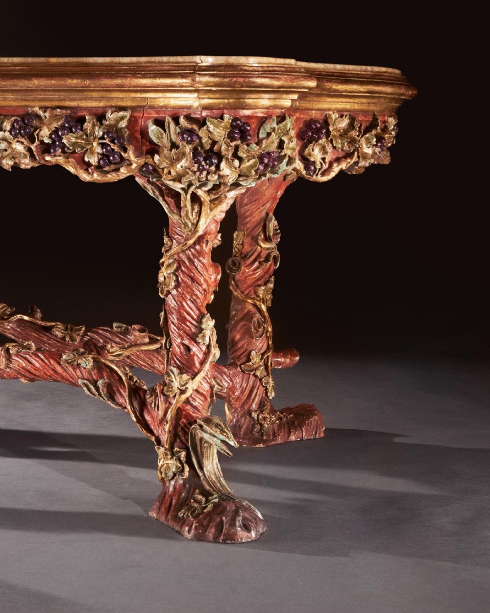 An ornate Italian centre table featuring a sunburst pattern onyx top supported by a sculpted polychrome and gilded wooden frame shaped like grapevine branches. View VII