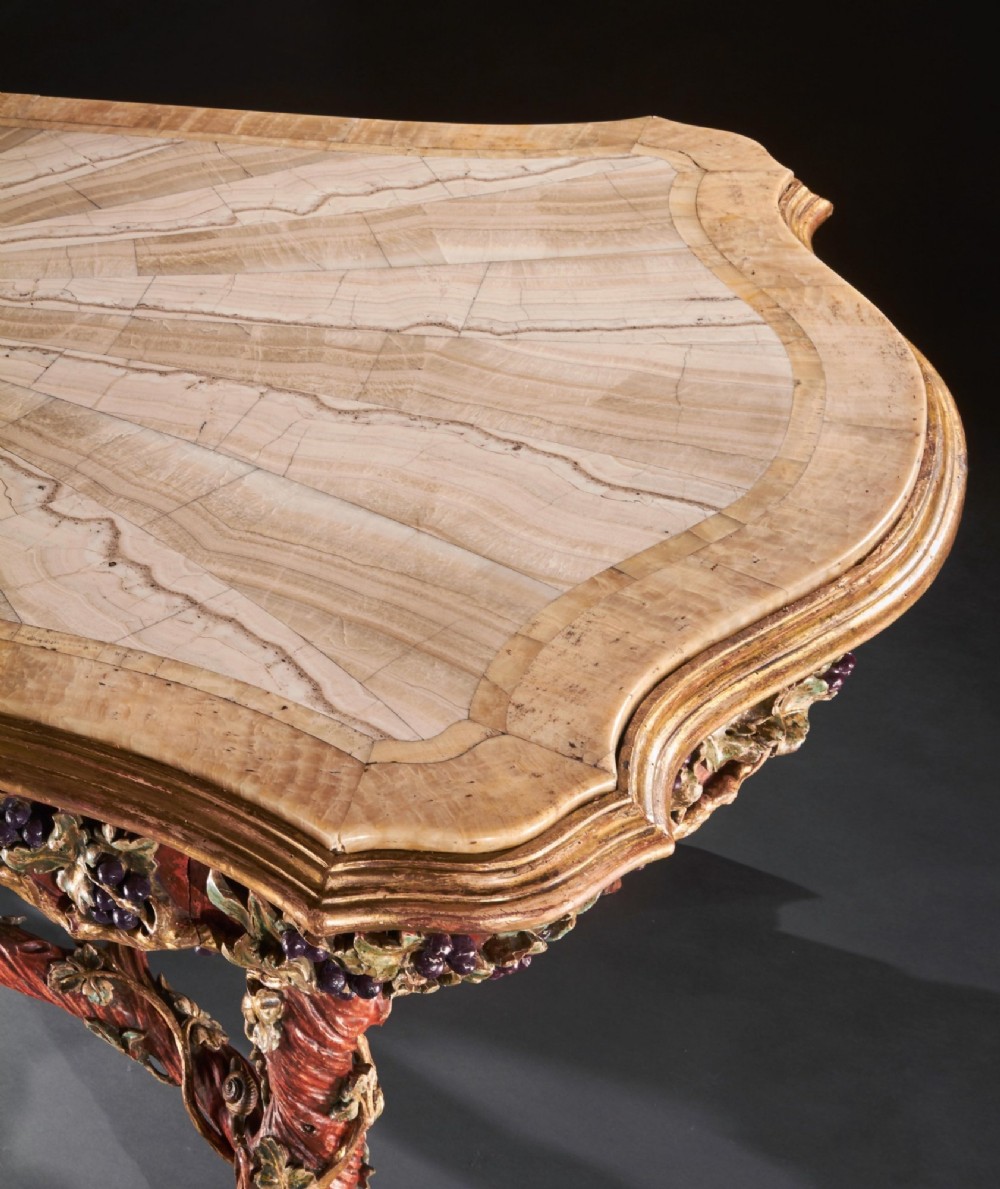 An ornate Italian centre table featuring a sunburst pattern onyx top supported by a sculpted polychrome and gilded wooden frame shaped like grapevine branches. View VIII