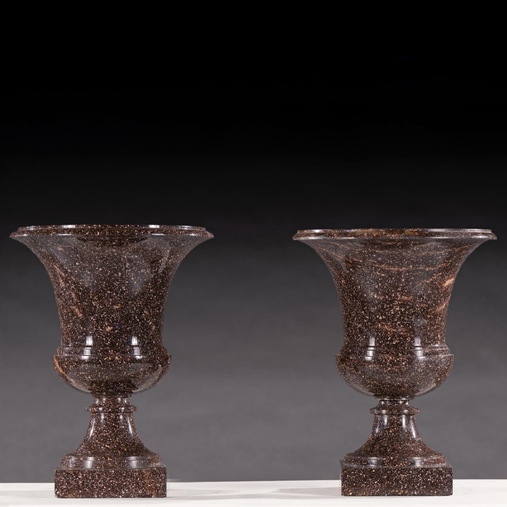 A pair of polished dark brown speckled porphyry stone urns crafted in the classical Campana shape with flared rims and square bases. View II