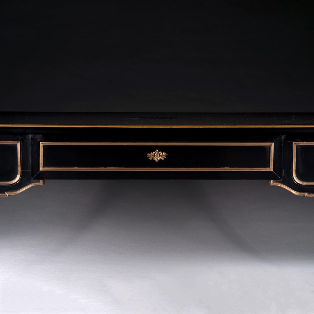 A late nineteenth-century French ebonised writing desk featuring gilt mouldings, three frieze drawers, and slender fluted tapered legs. View II
