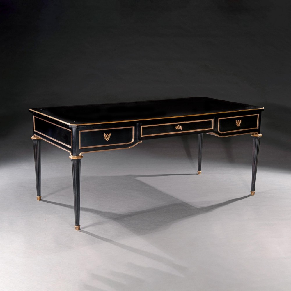 A late nineteenth-century French ebonised writing desk featuring gilt mouldings, three frieze drawers, and slender fluted tapered legs. View V