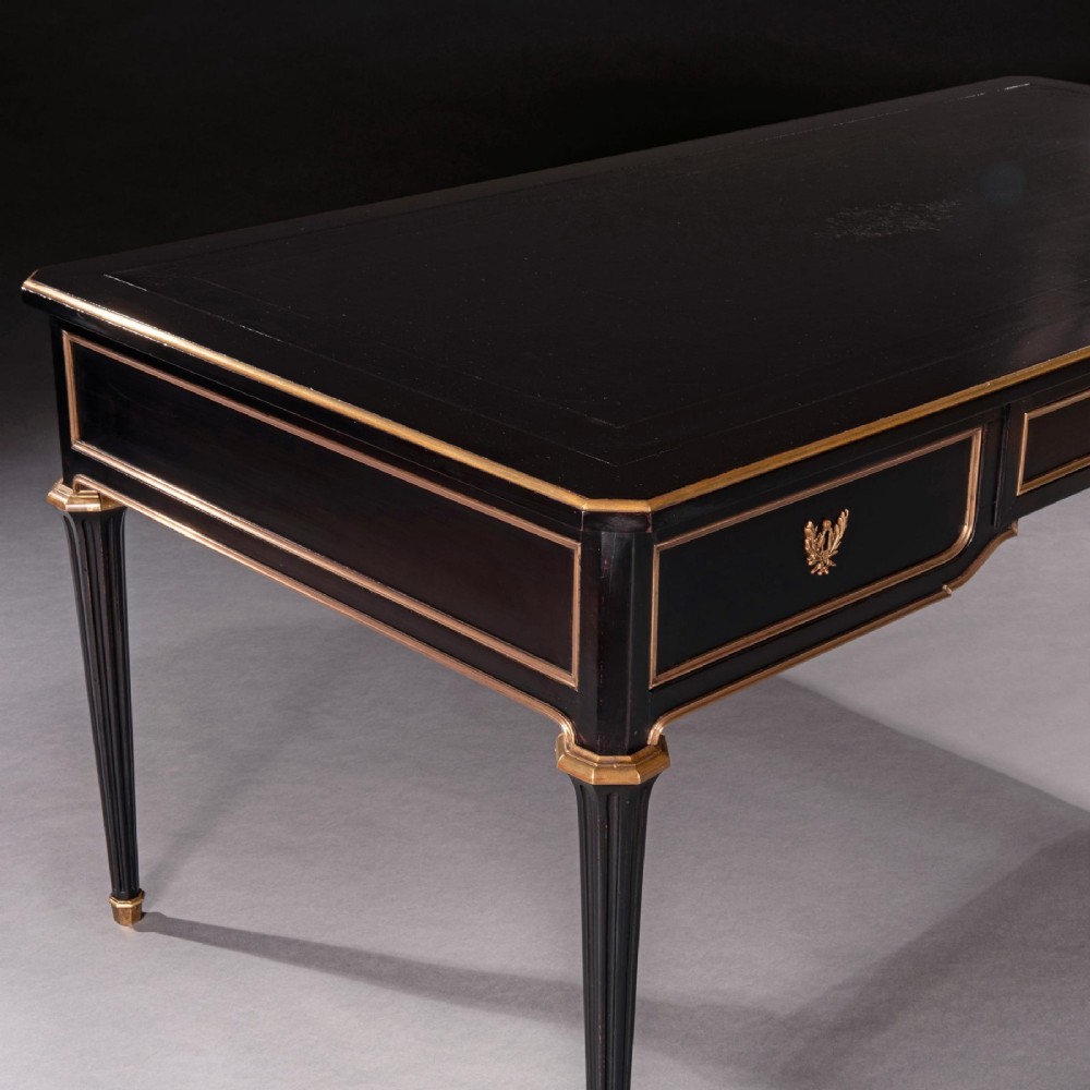 A late nineteenth-century French ebonised writing desk featuring gilt mouldings, three frieze drawers, and slender fluted tapered legs. View VI