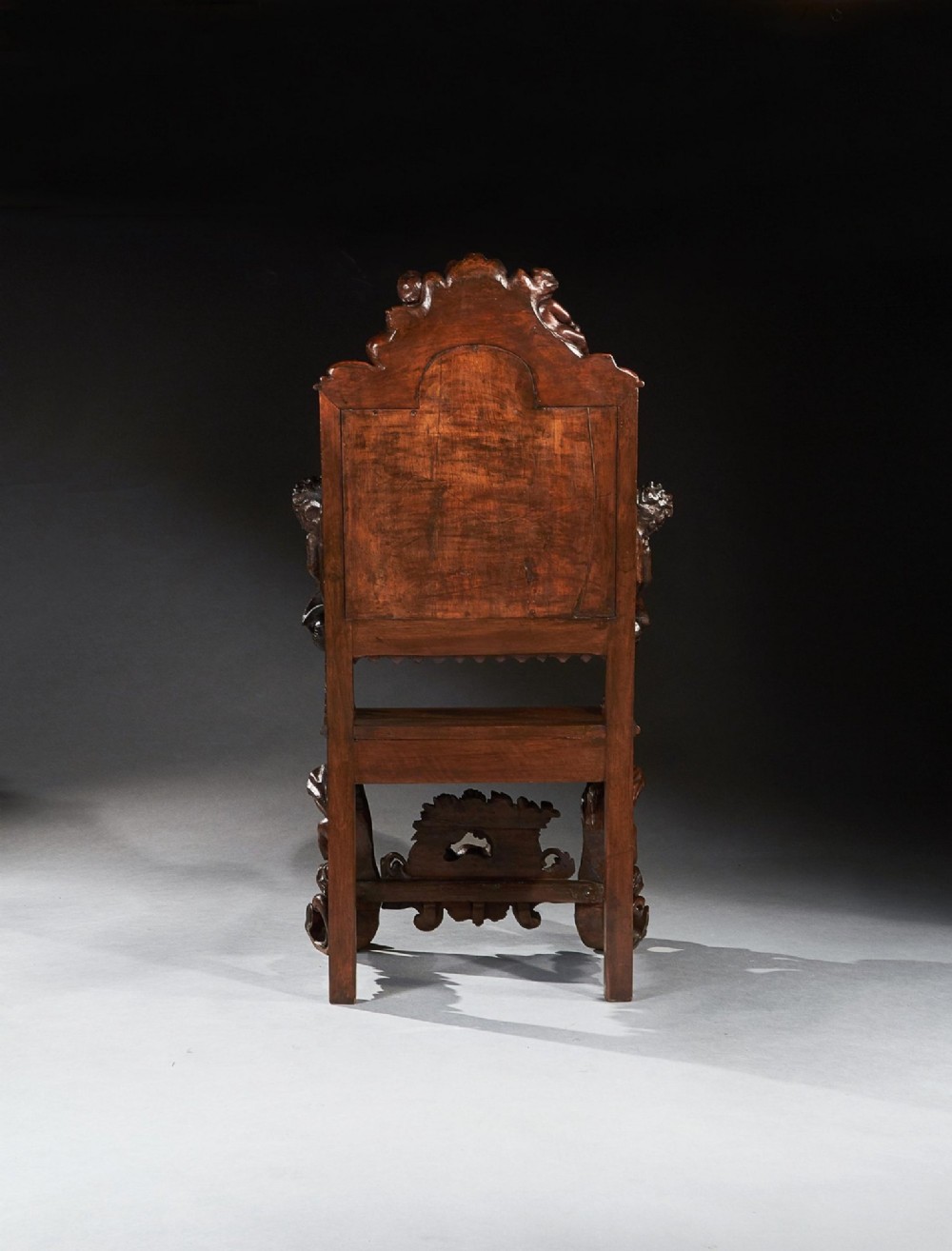 A 19th-century Italian carved walnut armchair featuring elaborate sculptural figural supports and an embossed high backrest. View V