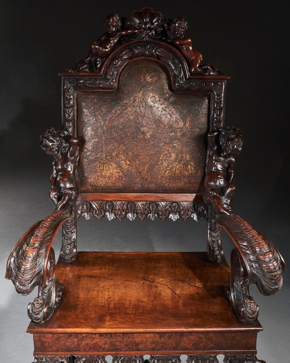 A 19th-century Italian carved walnut armchair featuring elaborate sculptural figural supports and an embossed high backrest. View VI
