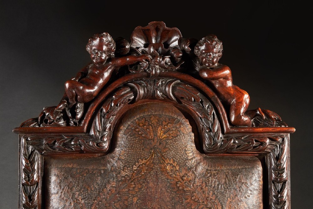 A 19th-century Italian carved walnut armchair featuring elaborate sculptural figural supports and an embossed high backrest. View VII