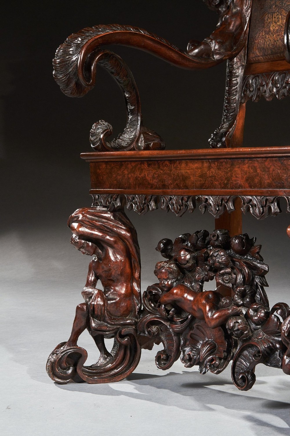 A 19th-century Italian carved walnut armchair featuring elaborate sculptural figural supports and an embossed high backrest. View X