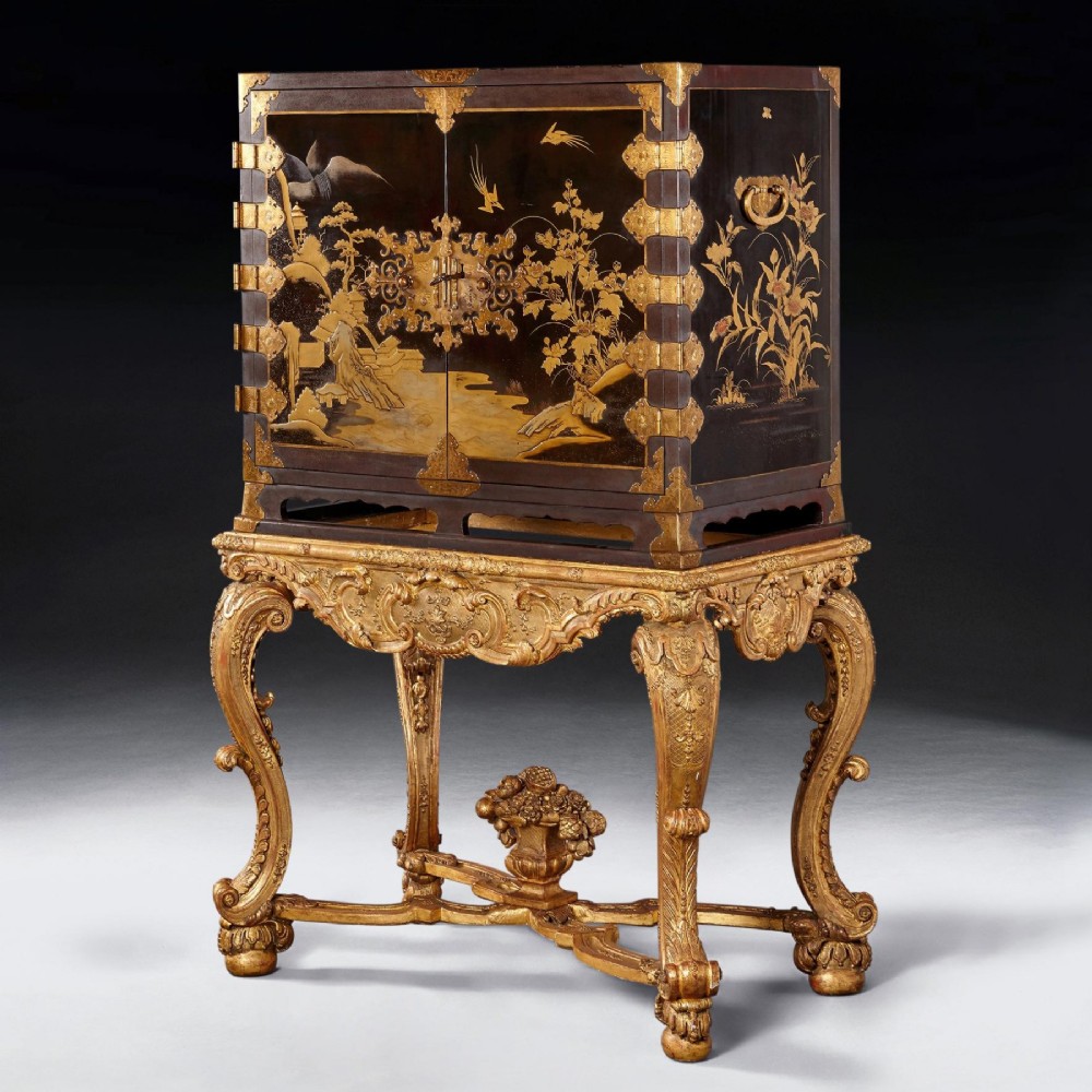 A black Japanese urushi lacquer cabinet decorated with gold landscape scenes and metal corner mounts, supported on a carved French Regence giltwood stand with cabriole legs. View II