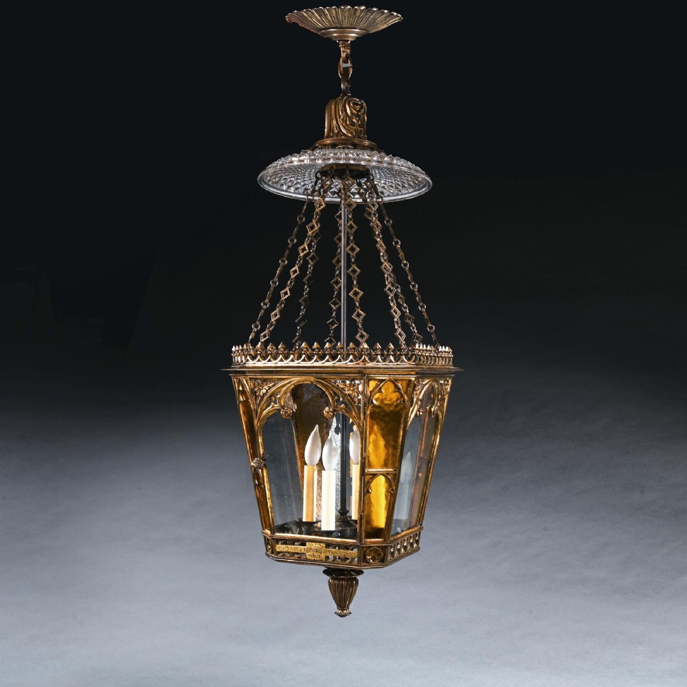 A Regency gilt brass hall lantern featuring Gothic tracery arches, glass side panels, an upper cut-glass shade, and a hanging chain.