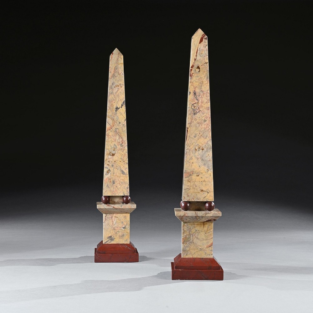 A pair of tall, veined marble obelisks carved from Portasanta and Rosso Antico marble with polished spherical details on tiered square bases. View IV
