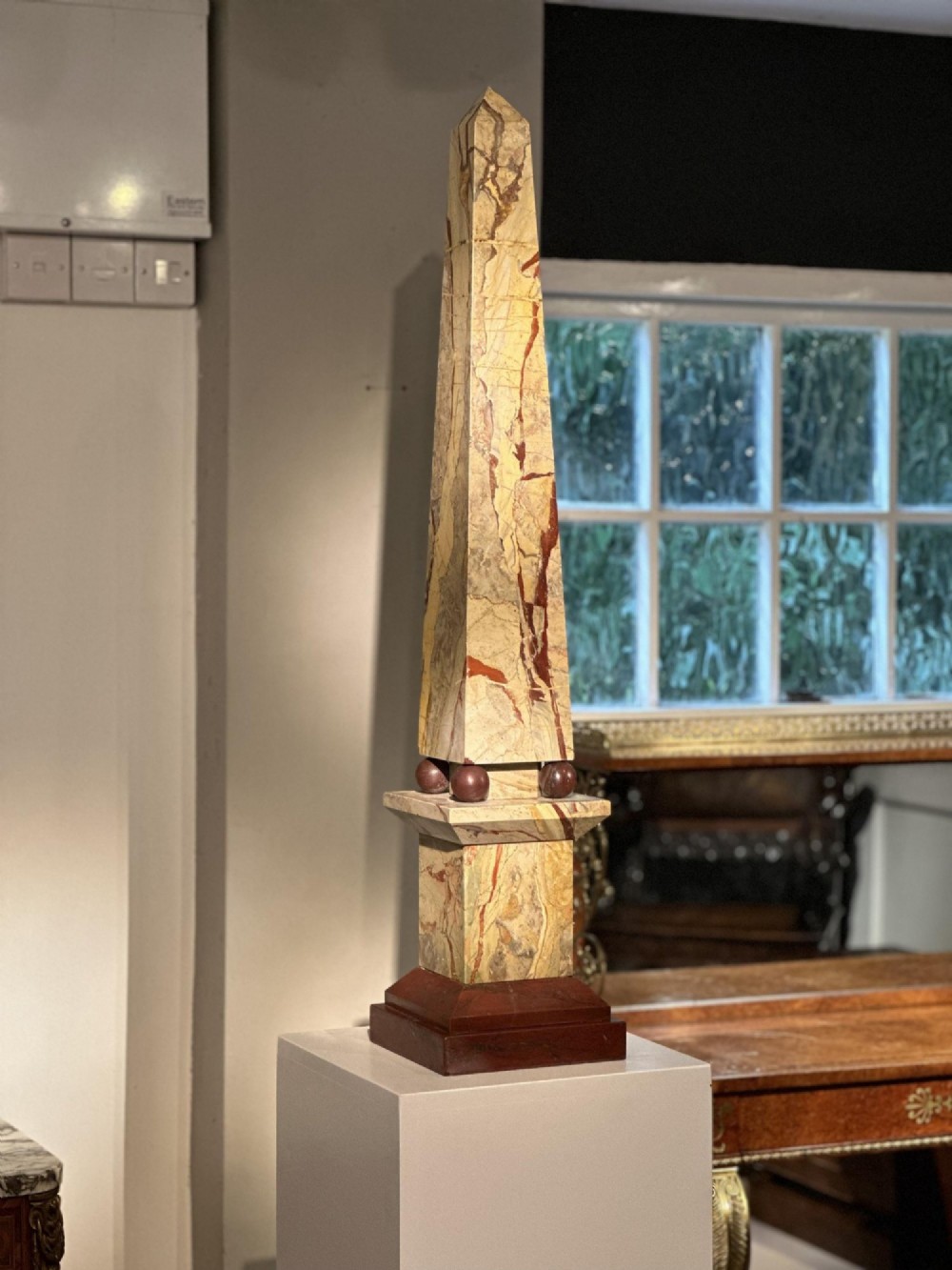 A pair of tall, veined marble obelisks carved from Portasanta and Rosso Antico marble with polished spherical details on tiered square bases. View VIII
