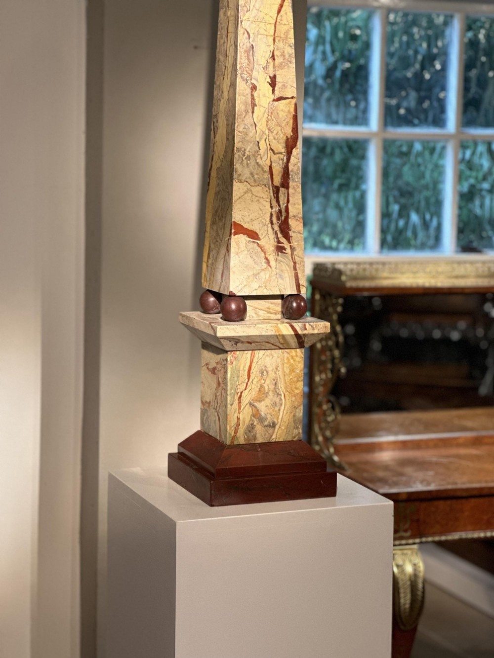 A pair of tall, veined marble obelisks carved from Portasanta and Rosso Antico marble with polished spherical details on tiered square bases. View IX
