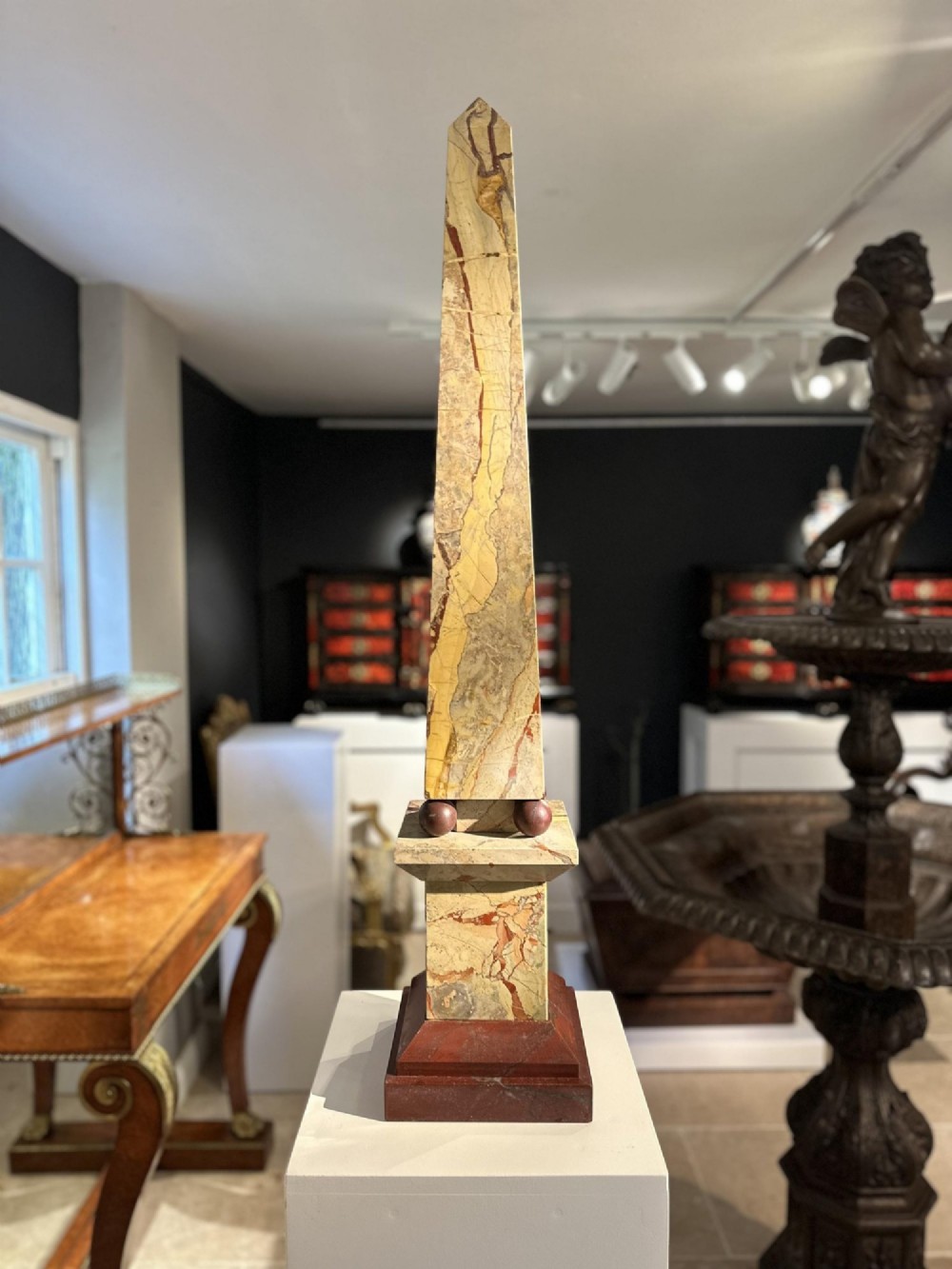 A pair of tall, veined marble obelisks carved from Portasanta and Rosso Antico marble with polished spherical details on tiered square bases. View XI