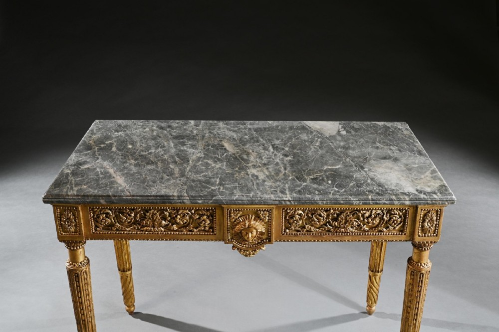 An 18th-century Italian Neoclassical console table featuring a grey veined marble top, an intricate giltwood frieze with a central carved mask, and fluted legs. View VI