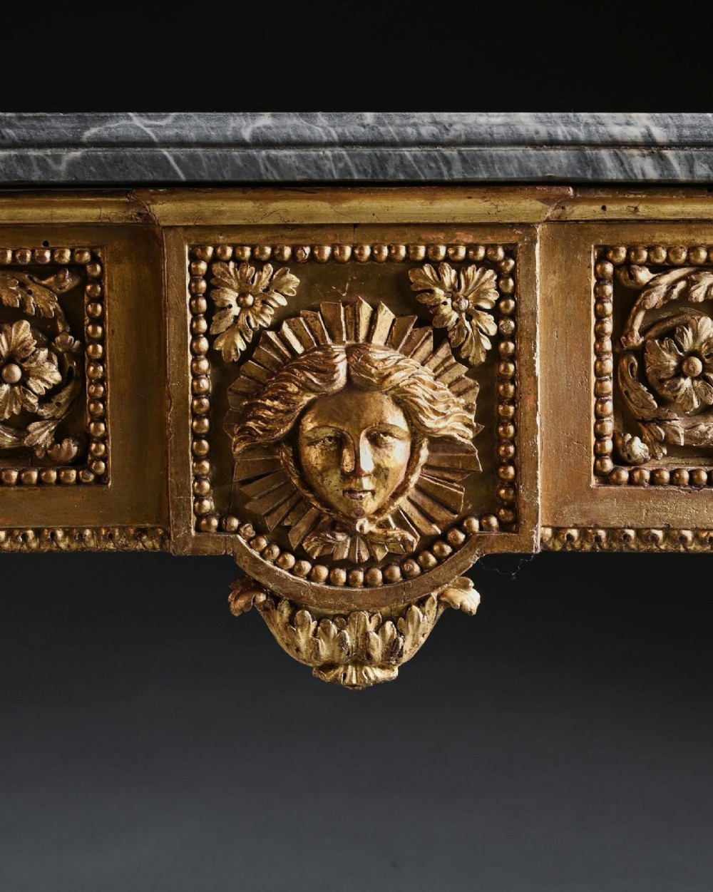 An 18th-century Italian Neoclassical console table featuring a grey veined marble top, an intricate giltwood frieze with a central carved mask, and fluted legs. View VIII