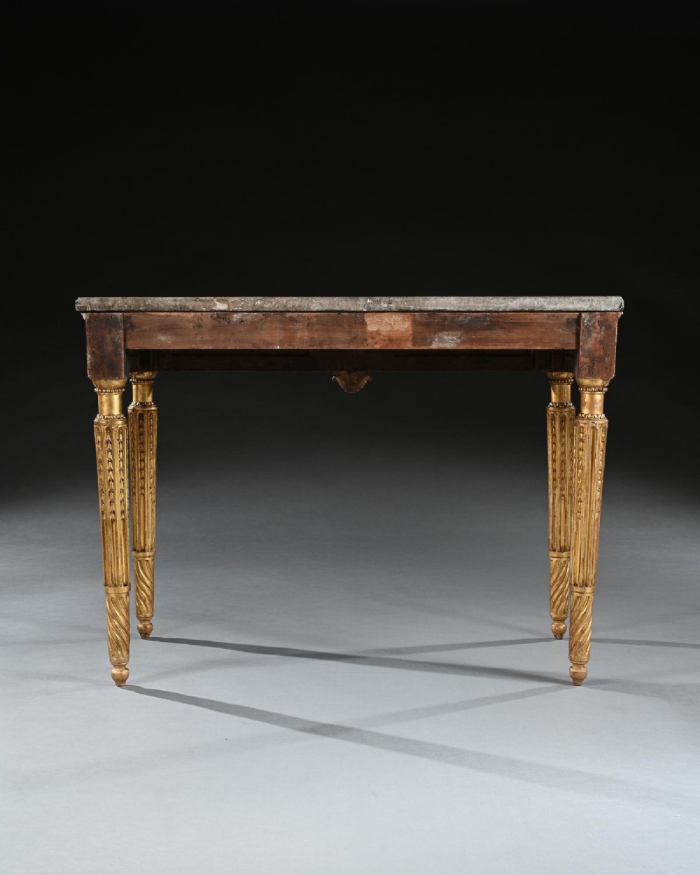 An 18th-century Italian Neoclassical console table featuring a grey veined marble top, an intricate giltwood frieze with a central carved mask, and fluted legs. View IX