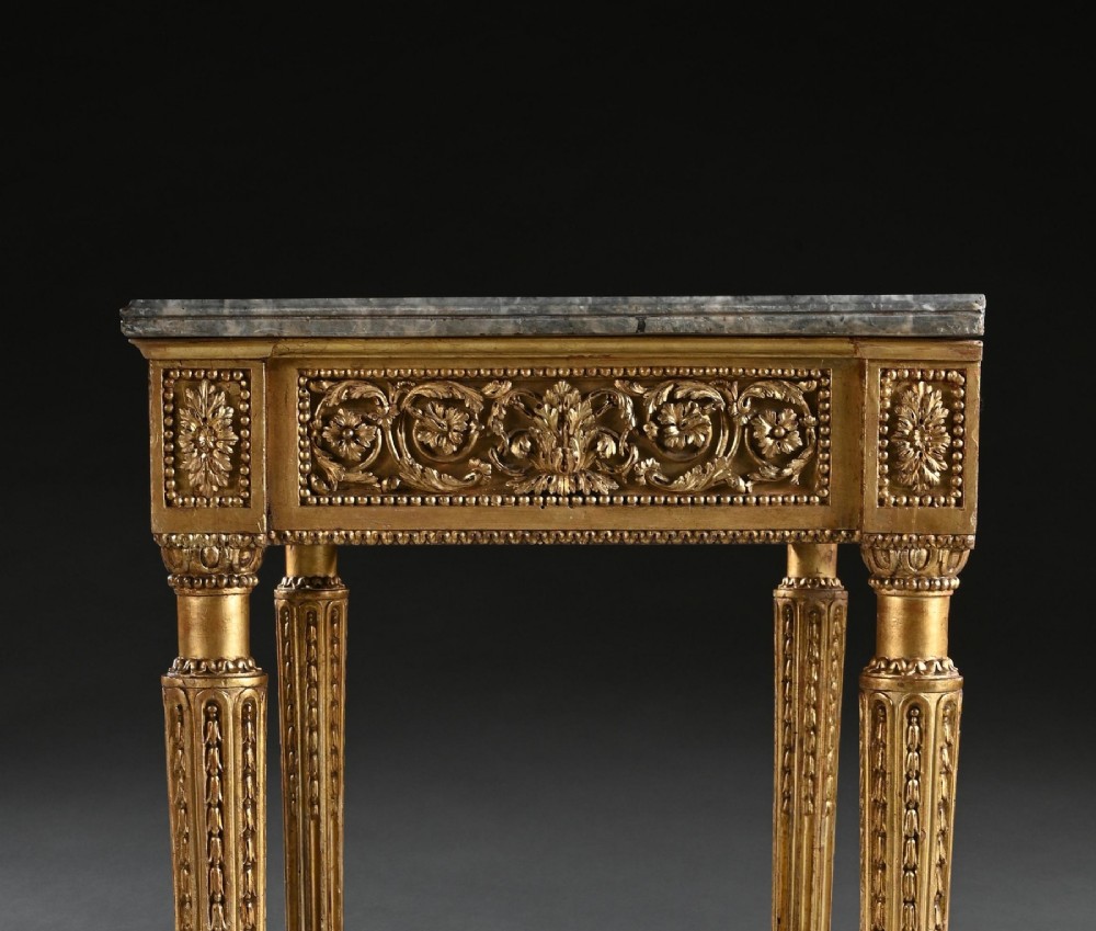 An 18th-century Italian Neoclassical console table featuring a grey veined marble top, an intricate giltwood frieze with a central carved mask, and fluted legs. View X