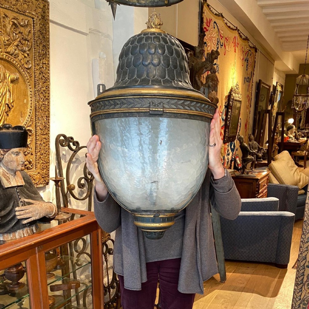 A pair of early 19th-century French tole peinte wall lanterns featuring imbricated scale domes, flame finials, and parcel gilt leaf borders over curved textured glass. View VIII