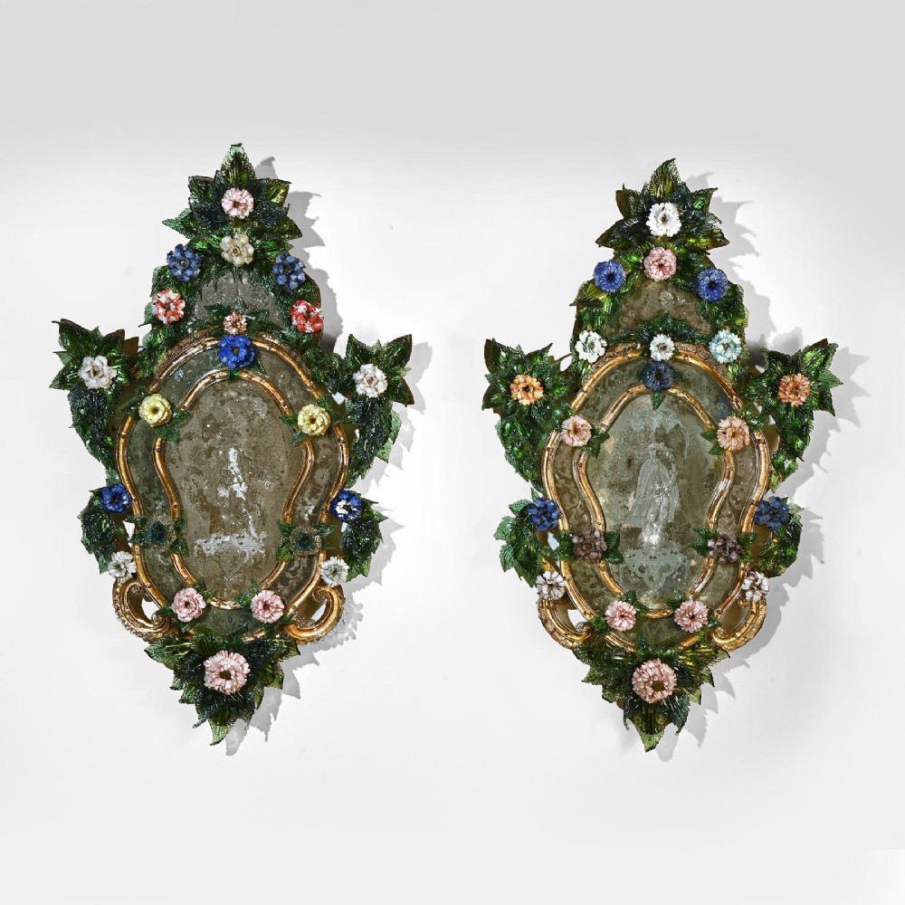 A pair of 18th-century Venetian Murano glass wall mirrors featuring decorative glass foliage, colourful glass flowers, etched central mirror plates, and gilt accents.