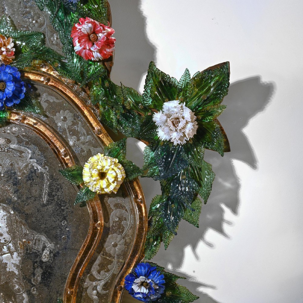 A pair of 18th-century Venetian Murano glass wall mirrors featuring decorative glass foliage, colourful glass flowers, etched central mirror plates, and gilt accents. View V