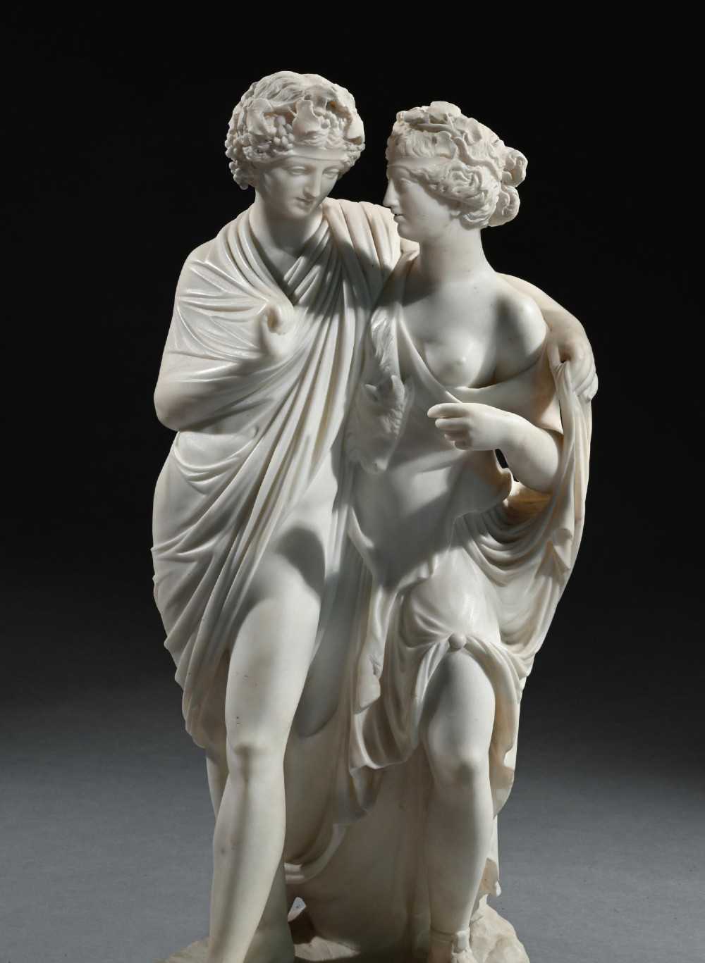 A hand-carved white marble Neoclassical sculpture depicting the classical mythological figures of Bacchus and Ariadne standing together on a circular integral base. View IV