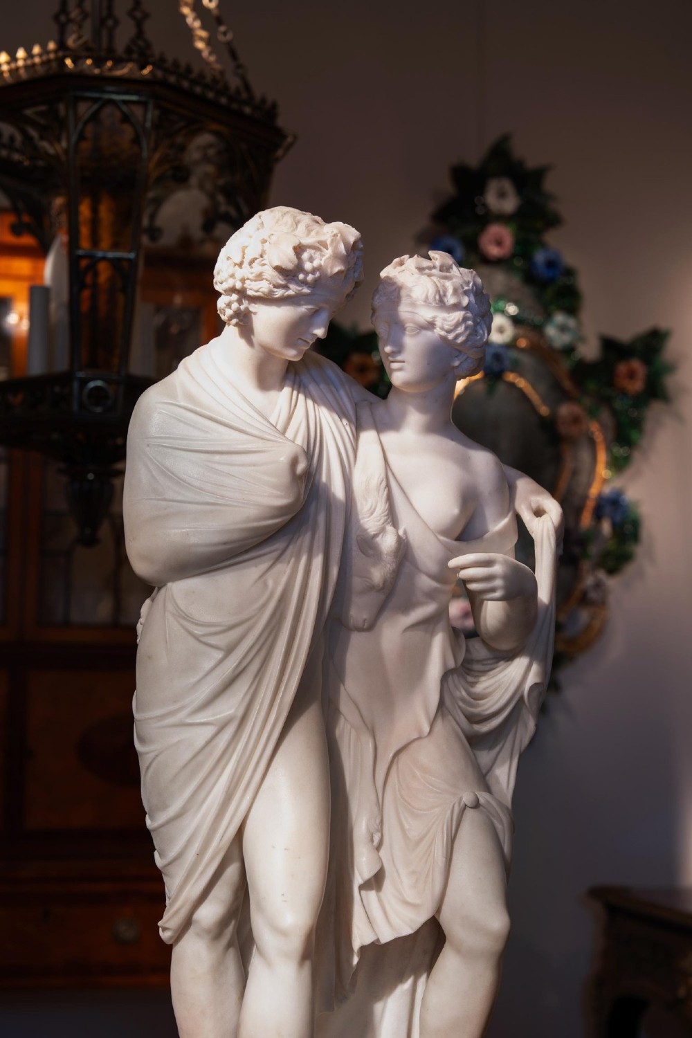 A hand-carved white marble Neoclassical sculpture depicting the classical mythological figures of Bacchus and Ariadne standing together on a circular integral base. View VI