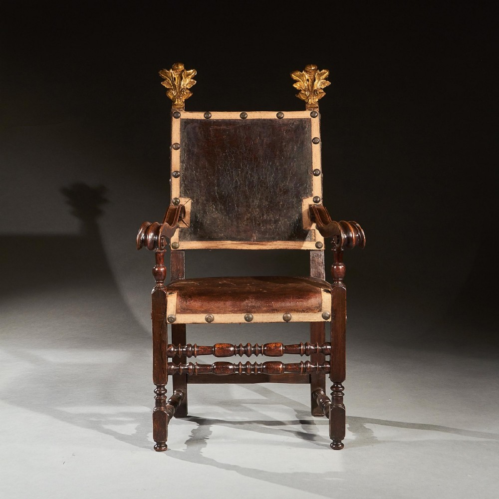 A pair of seventeenth-century Italian Baroque walnut armchairs featuring dark brown leather upholstery, decorative brass studs, turned stretchers, and gilded acanthus leaf finials. View II