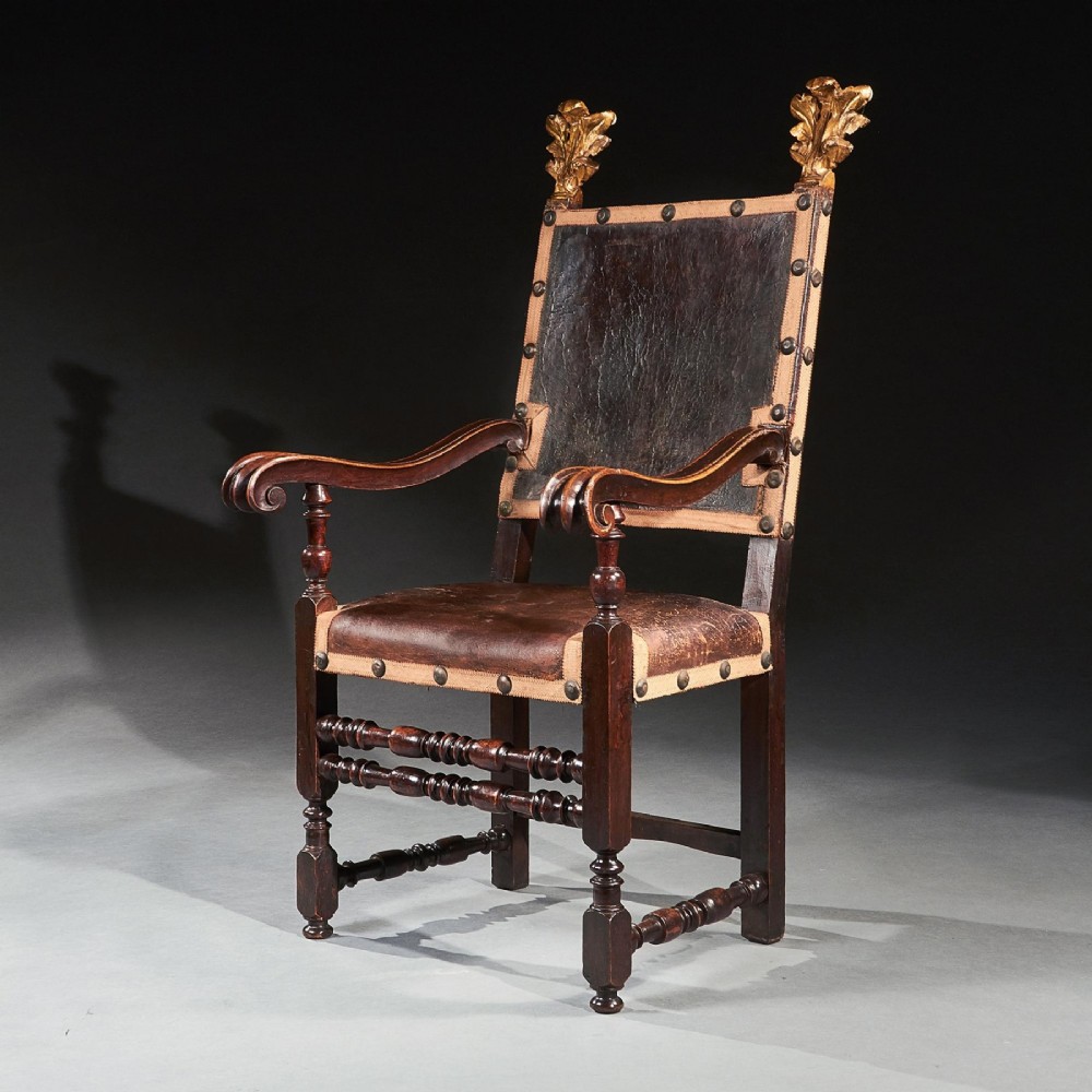 A pair of seventeenth-century Italian Baroque walnut armchairs featuring dark brown leather upholstery, decorative brass studs, turned stretchers, and gilded acanthus leaf finials. View III