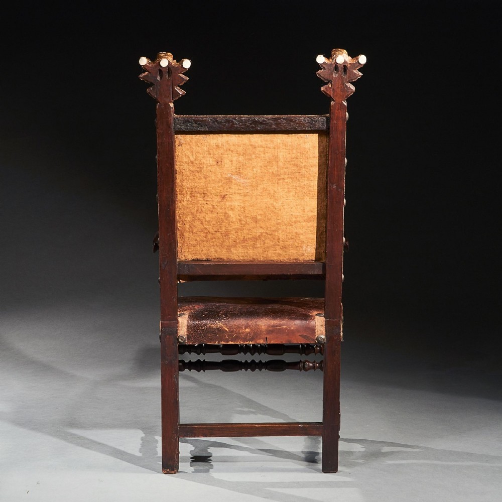 A pair of seventeenth-century Italian Baroque walnut armchairs featuring dark brown leather upholstery, decorative brass studs, turned stretchers, and gilded acanthus leaf finials. View IV