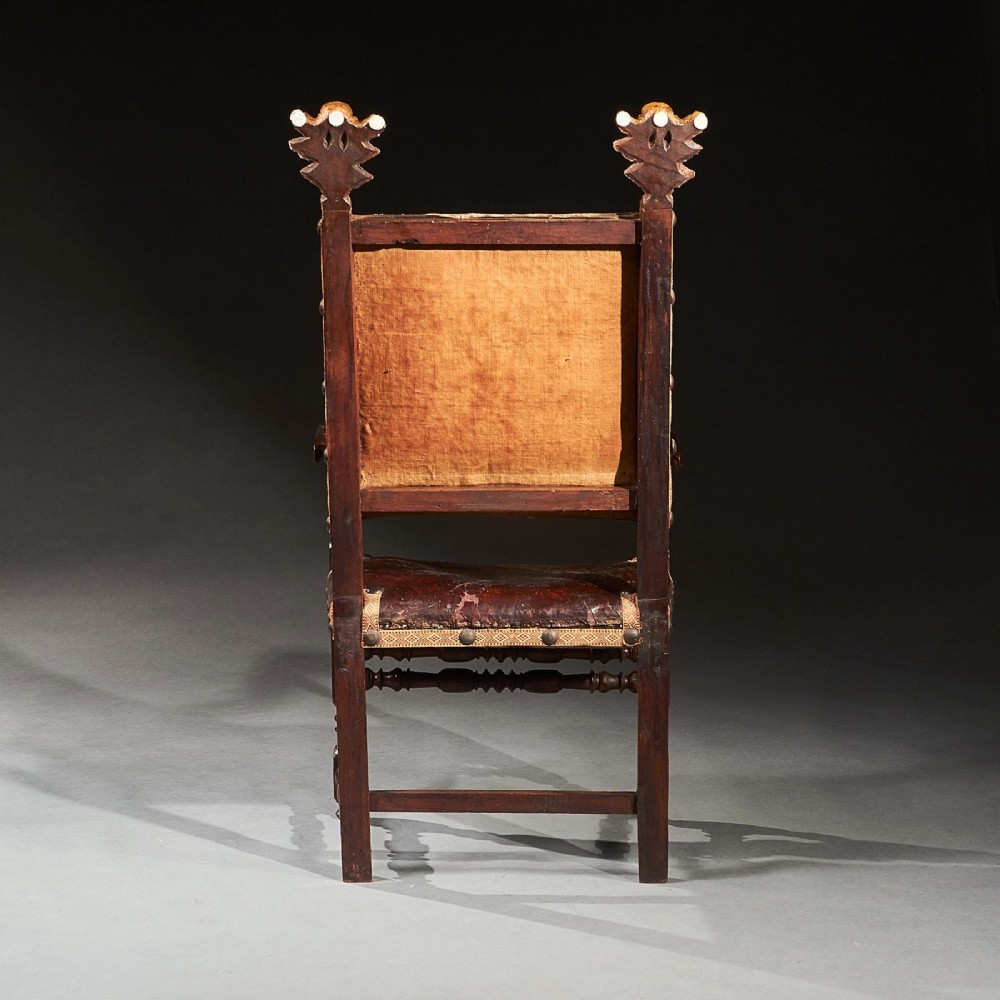 A pair of seventeenth-century Italian Baroque walnut armchairs featuring dark brown leather upholstery, decorative brass studs, turned stretchers, and gilded acanthus leaf finials. View VII