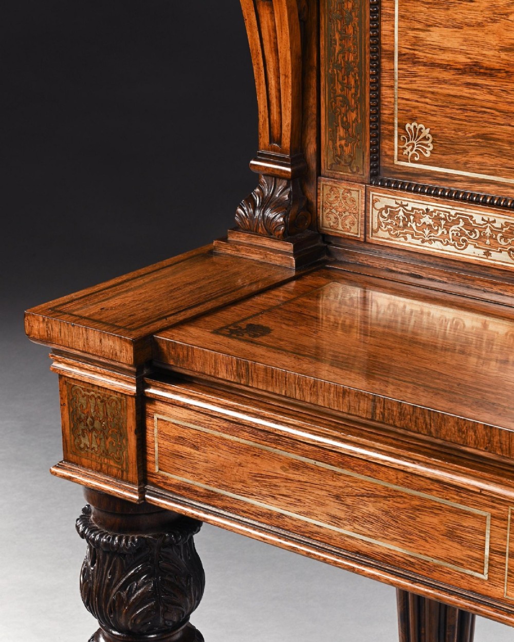 A Regency rosewood writing table featuring intricate brass scrollwork inlay, an anthemion top gallery, a central frieze drawer, and carved reeded legs. View III
