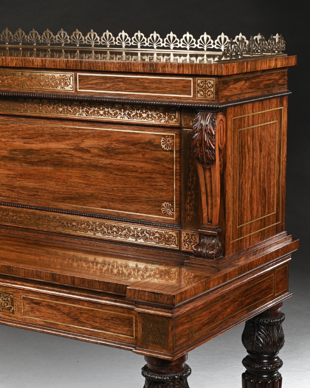 A Regency rosewood writing table featuring intricate brass scrollwork inlay, an anthemion top gallery, a central frieze drawer, and carved reeded legs. View V