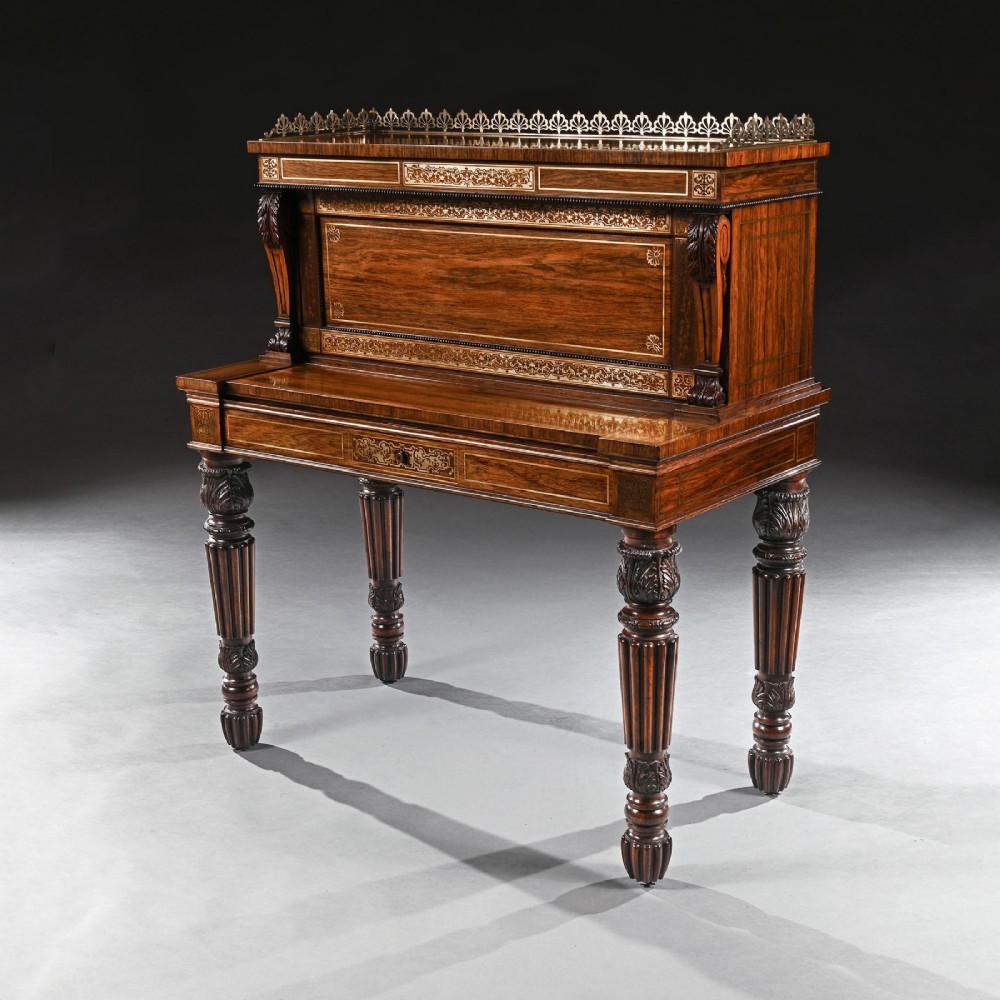 A Regency rosewood writing table featuring intricate brass scrollwork inlay, an anthemion top gallery, a central frieze drawer, and carved reeded legs. View VI