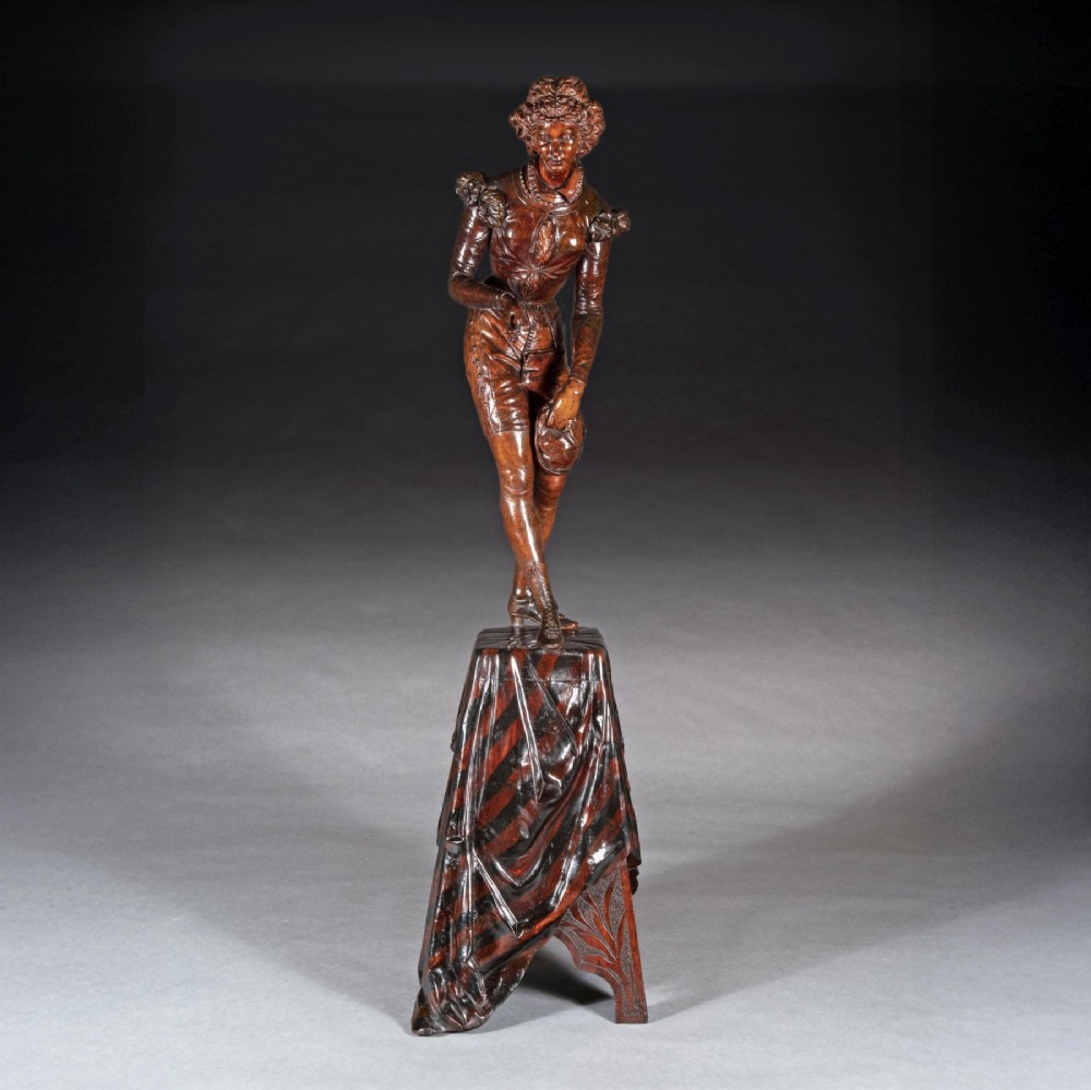 A pair of carved brown wood figures depicting Renaissance figures atop detailed wooden bases. View V