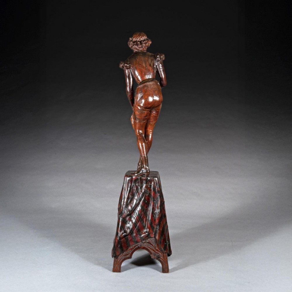 A pair of carved brown wood figures depicting Renaissance figures atop detailed wooden bases. View X