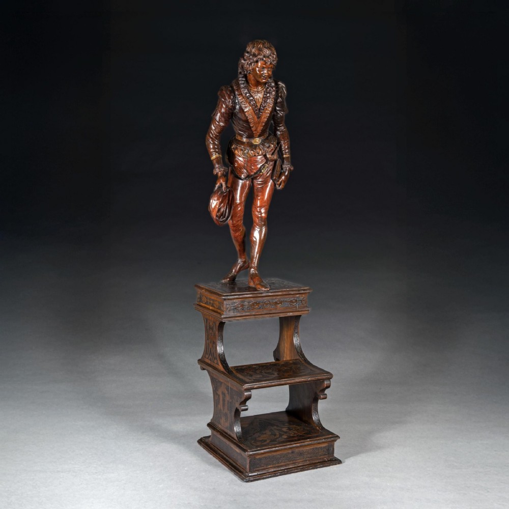 A pair of carved brown wood figures depicting Renaissance figures atop detailed wooden bases. View XI