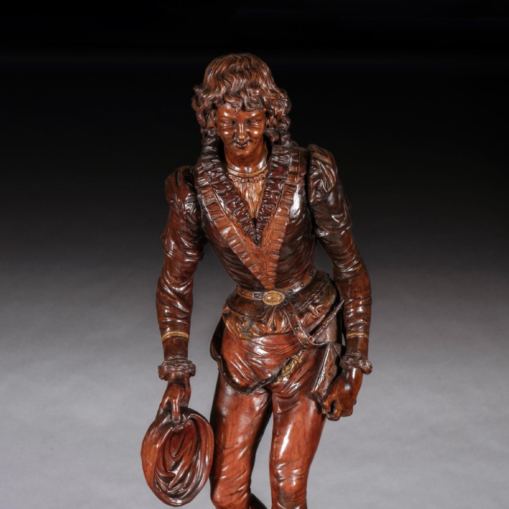 A pair of carved brown wood figures depicting Renaissance figures atop detailed wooden bases. View XII