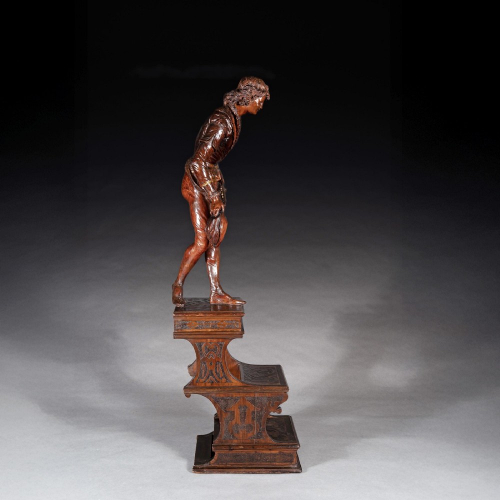 A pair of carved brown wood figures depicting Renaissance figures atop detailed wooden bases. View XIV