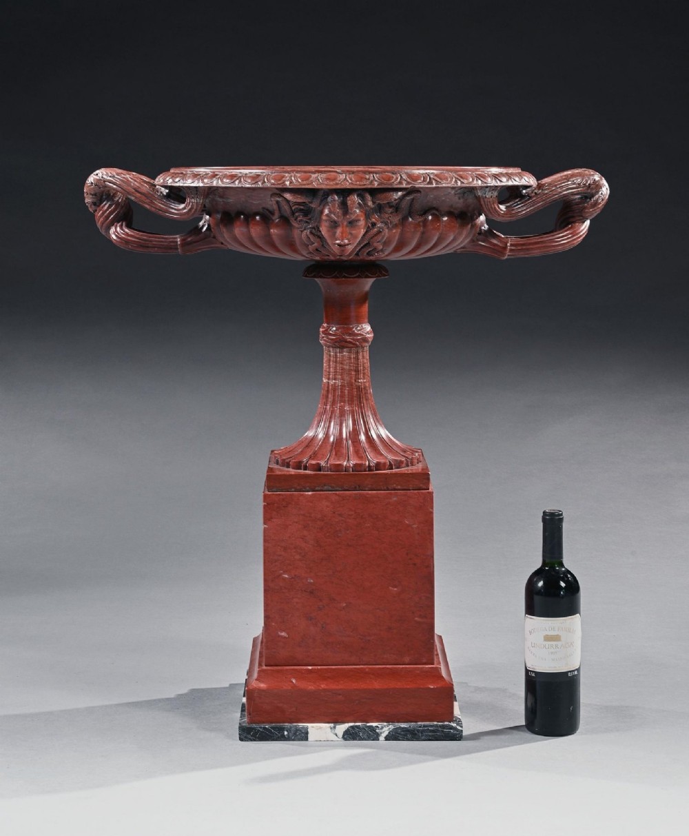 A carved deep red Rosso Antico marble tazza featuring serpent handles, a Medusa mask motif, and a fluted stem set upon a square pedestal base. View V