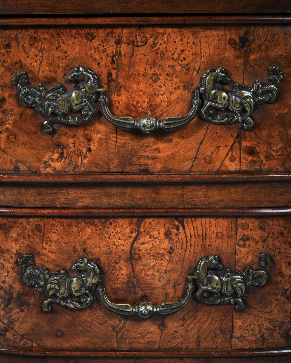 An eighteenth-century French provincial burr elm commode featuring three shaped drawers with ornate brass handles and escutcheons. View V