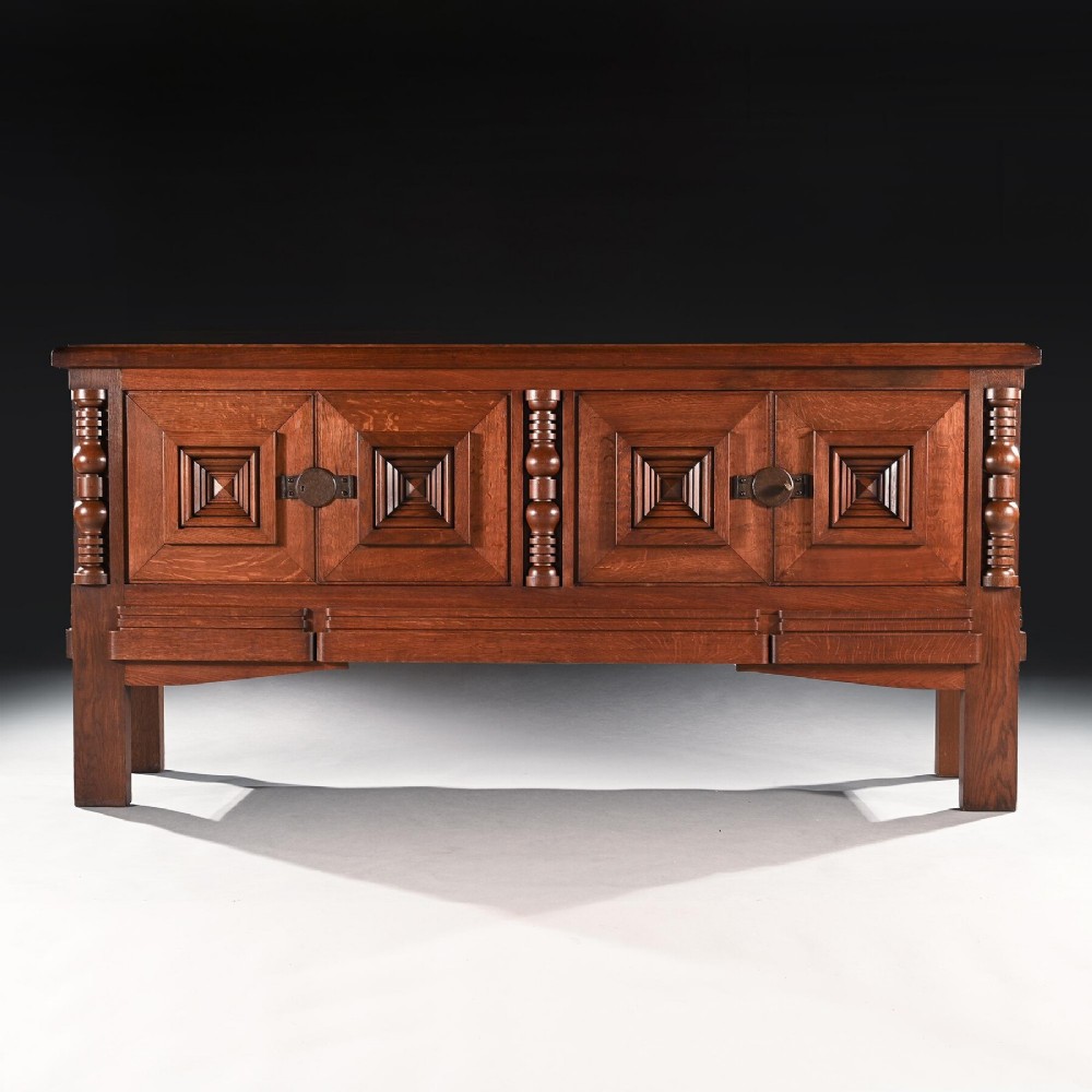 Mid-twentieth-century French oak sideboard featuring four cabinet doors with raised geometric diamond panels and turned wooden column accents.