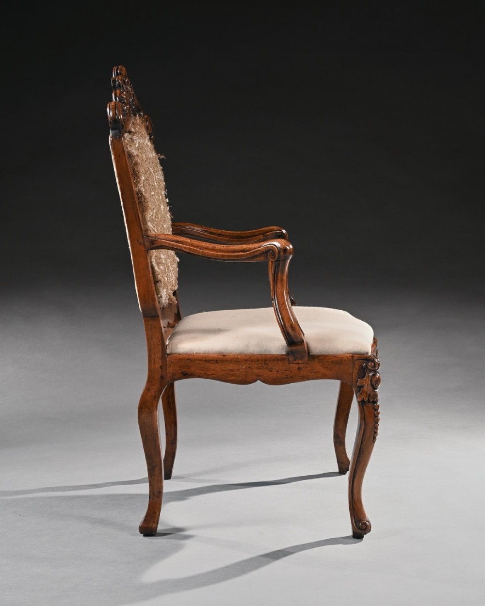 Mid-18th-century Italian Rococo carved walnut armchair featuring cabriole legs, curved armrests, an ornate carved mask crest rail, and exposed traditional back padding. View II