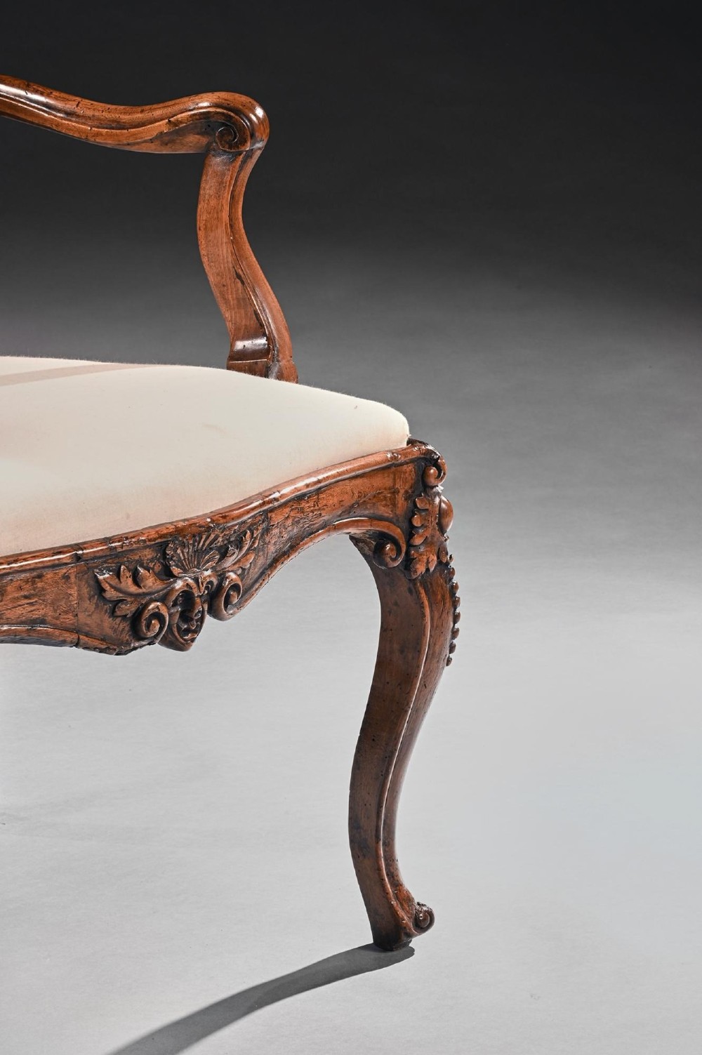 Mid-18th-century Italian Rococo carved walnut armchair featuring cabriole legs, curved armrests, an ornate carved mask crest rail, and exposed traditional back padding. View V
