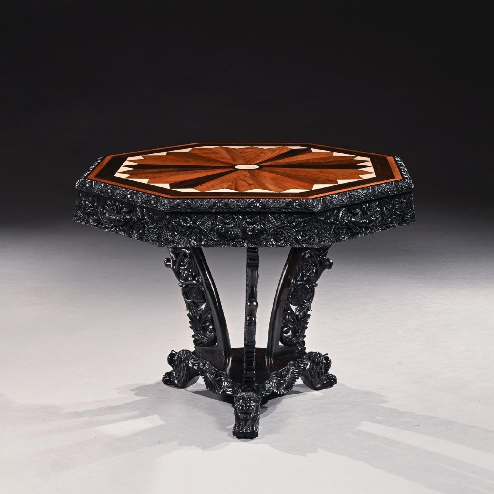 A 19th-century Ceylonese octagonal centre table crafted from dark ebony featuring a geometric starburst specimen wood inlaid top and deeply carved pedestal base. View III