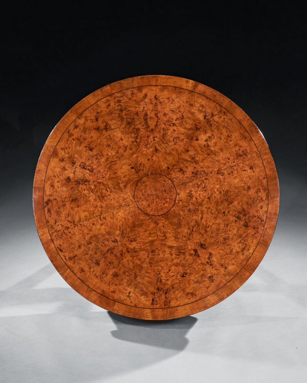 A circular early 19th-century Scandinavian drum table crafted from burr maple with frieze drawers, a lower shelf, and quadruped splayed legs with brass castors. View IV
