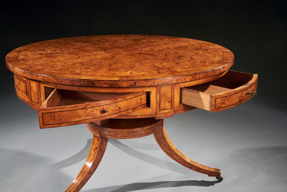 A circular early 19th-century Scandinavian drum table crafted from burr maple with frieze drawers, a lower shelf, and quadruped splayed legs with brass castors. View VI
