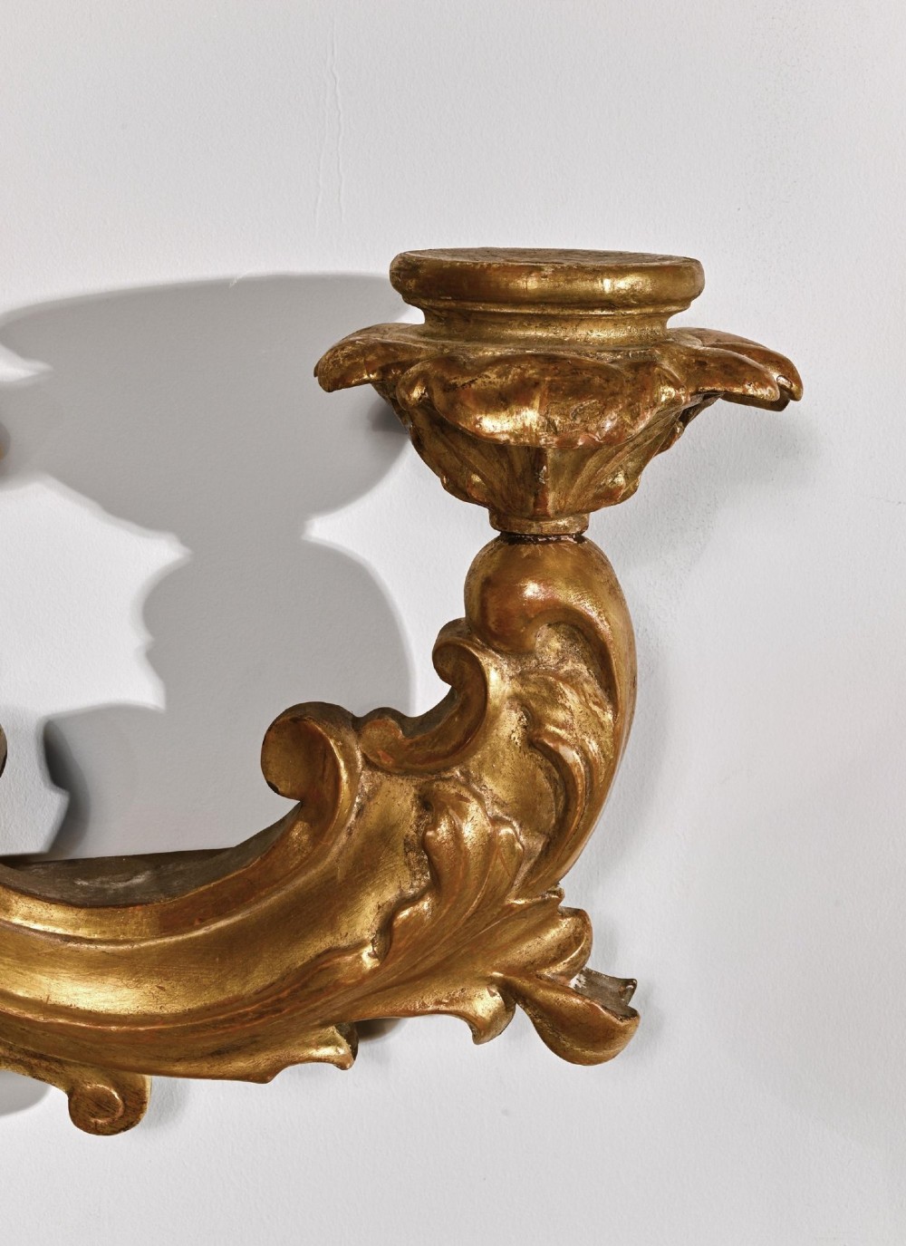 A pair of carved giltwood wall sconces featuring ornate rococo scrollwork, acanthus leaf motifs, and twin candle arms against a dark backdrop. View VI