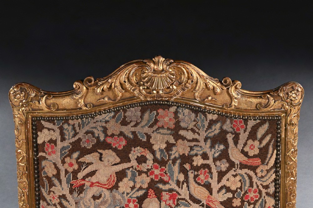 An 18th-century French Regence carved giltwood armchair featuring padded open armrests and tapestry upholstery depicting a figural and floral scene. View IV